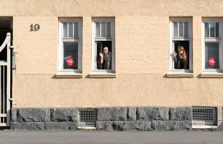 Valokuva mainostoimisto Design Inspiksen julkisivusta Koulukatu 19:ssä Oulussa. Design Inspiksen työntekijät vilkuttavat ikkunoista.