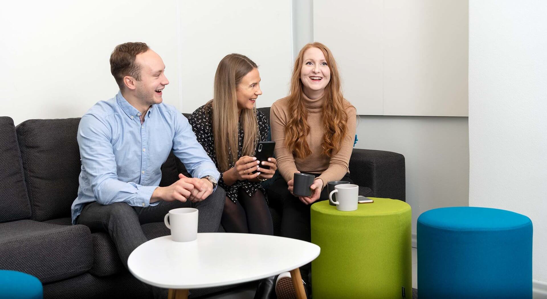 Digizerin työntekijät sohvalla keskustelemassa nauravaisina.