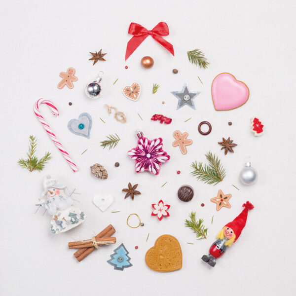 Valokuvattu jouluisia esineitä vaalealla taustalla, kokonaisuus muodostaa joulupallon muodon.