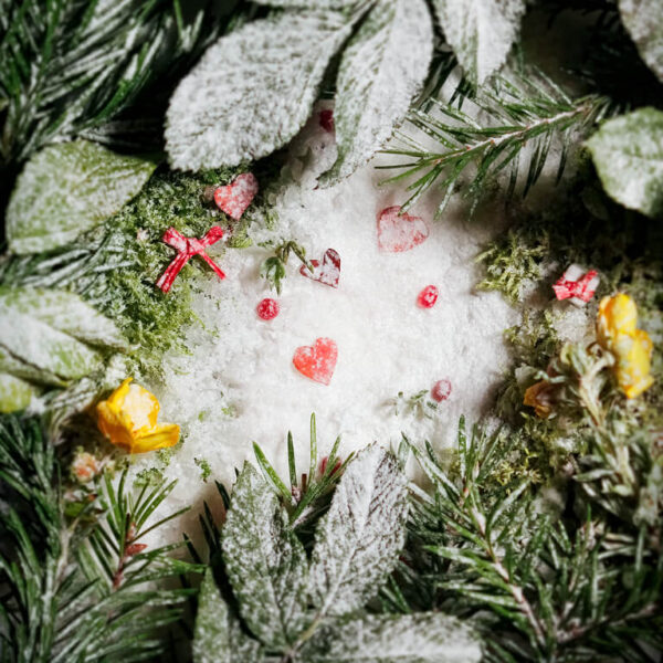 Valokuvattu jouluisa asetelma, lumisia lejtiä ja punaisia sydämiä sekä paketteja.